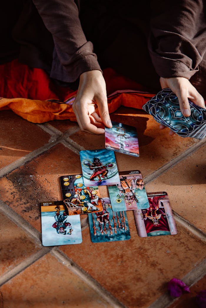 A close-up view of hands engaged in a tarot card reading on a tiled floor, creating a mystical atmosphere.